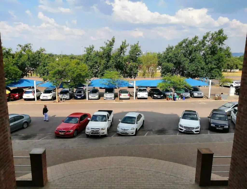 View looking out from Loapi House Gaborone at cars in free parking on road both for government departments and Loapi Business Centre offices
